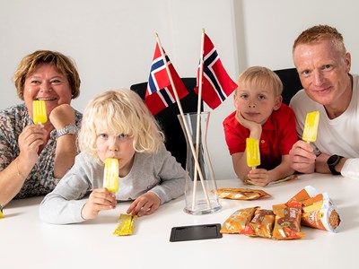 To voksne og to barn tester is i et rom med norske flagg