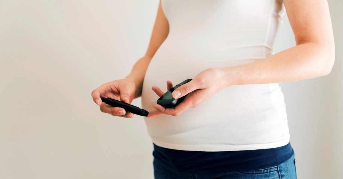En gravis kvinne som måler blodsukkeret med blodsukkermåler